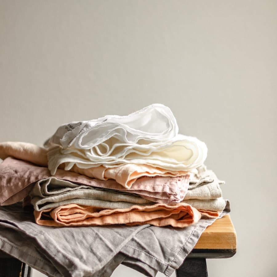 Freshly laundered linen folded in a stack on a wooden stool.